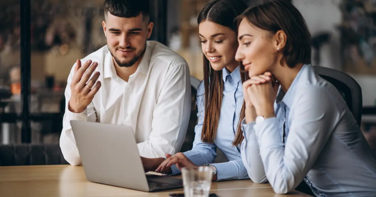 Empleados trabajando juntos en una oficina con una laptop con un software